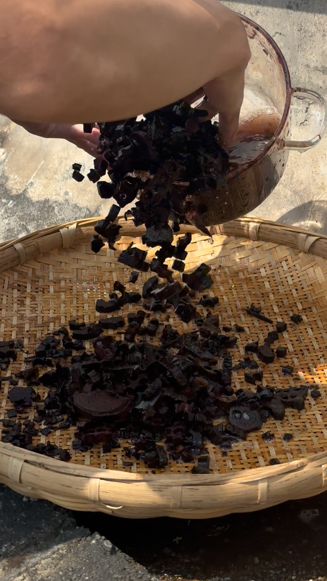 Processed jiangzhenxiang wood pieces being poured onto a bamboo drying tray