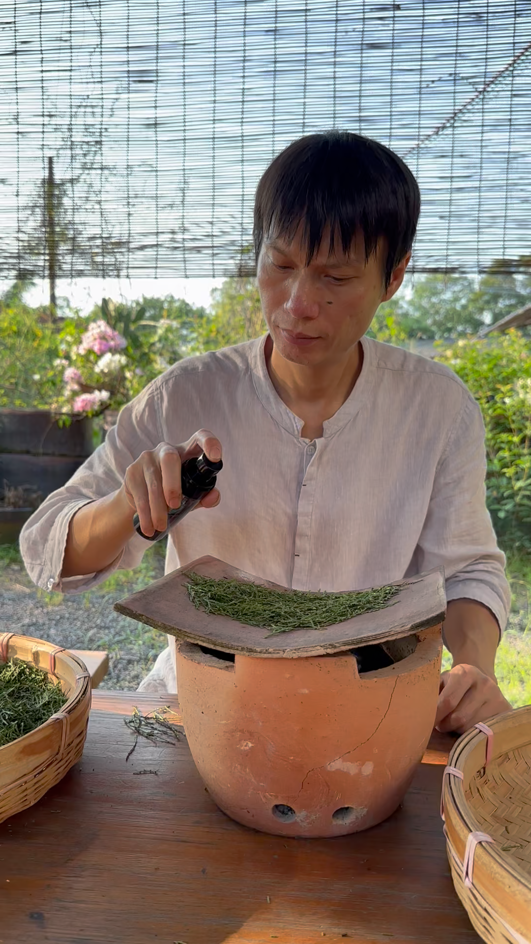 Chinese arborvitae leaves being stir-fried and processed with baijiu using the jiu zhi paozhi method